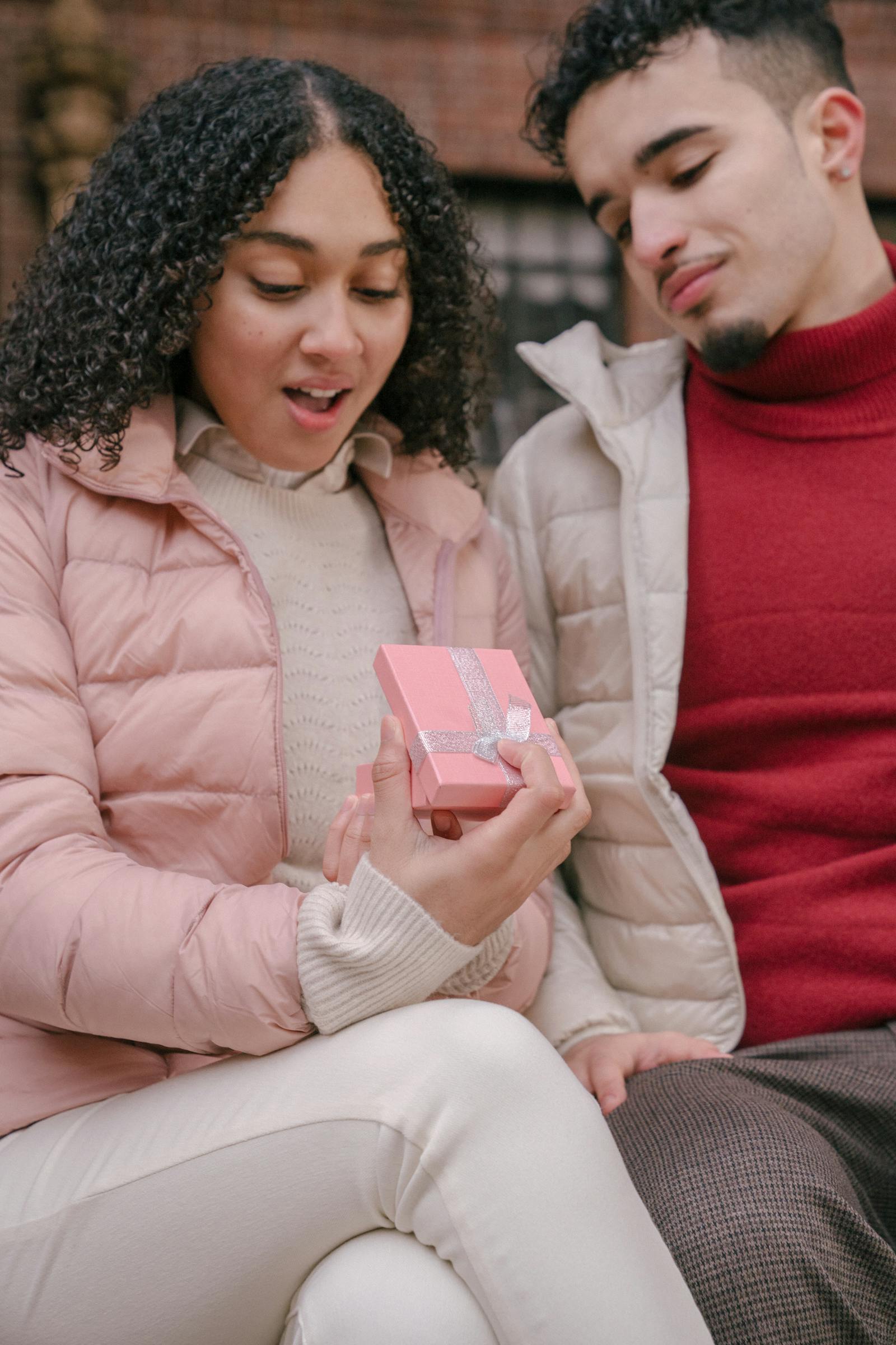 A surprised young woman opening a gift box