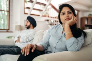 Couple sitting on a couch facing different ways looking frustrated. What You Can Do About It