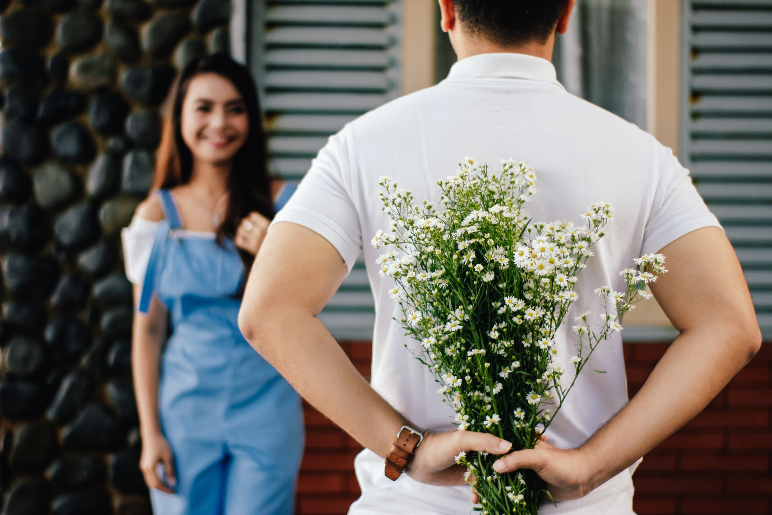 Couple facing each other, the man is holding flowers and the girl is smiling. You Can Truly Start Anew