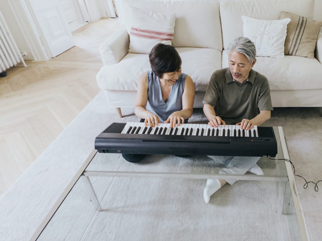 Couple sitting on the floor playing piano in an endearing way. Don’t singlehandedly kill your relationship.