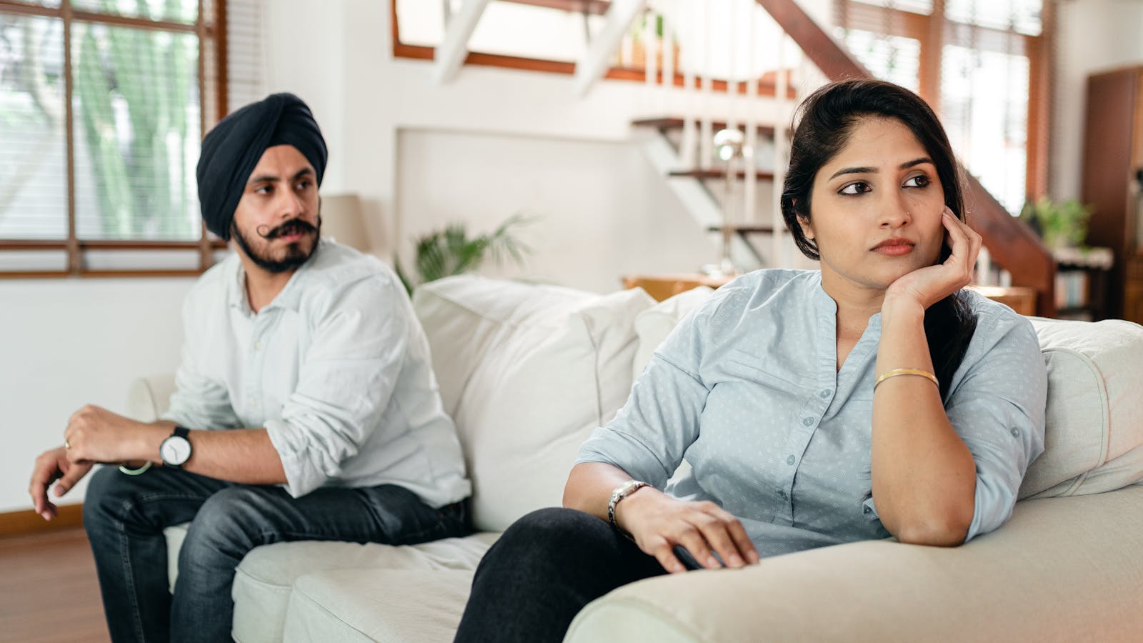 Unhappy couple sitting apart on couch