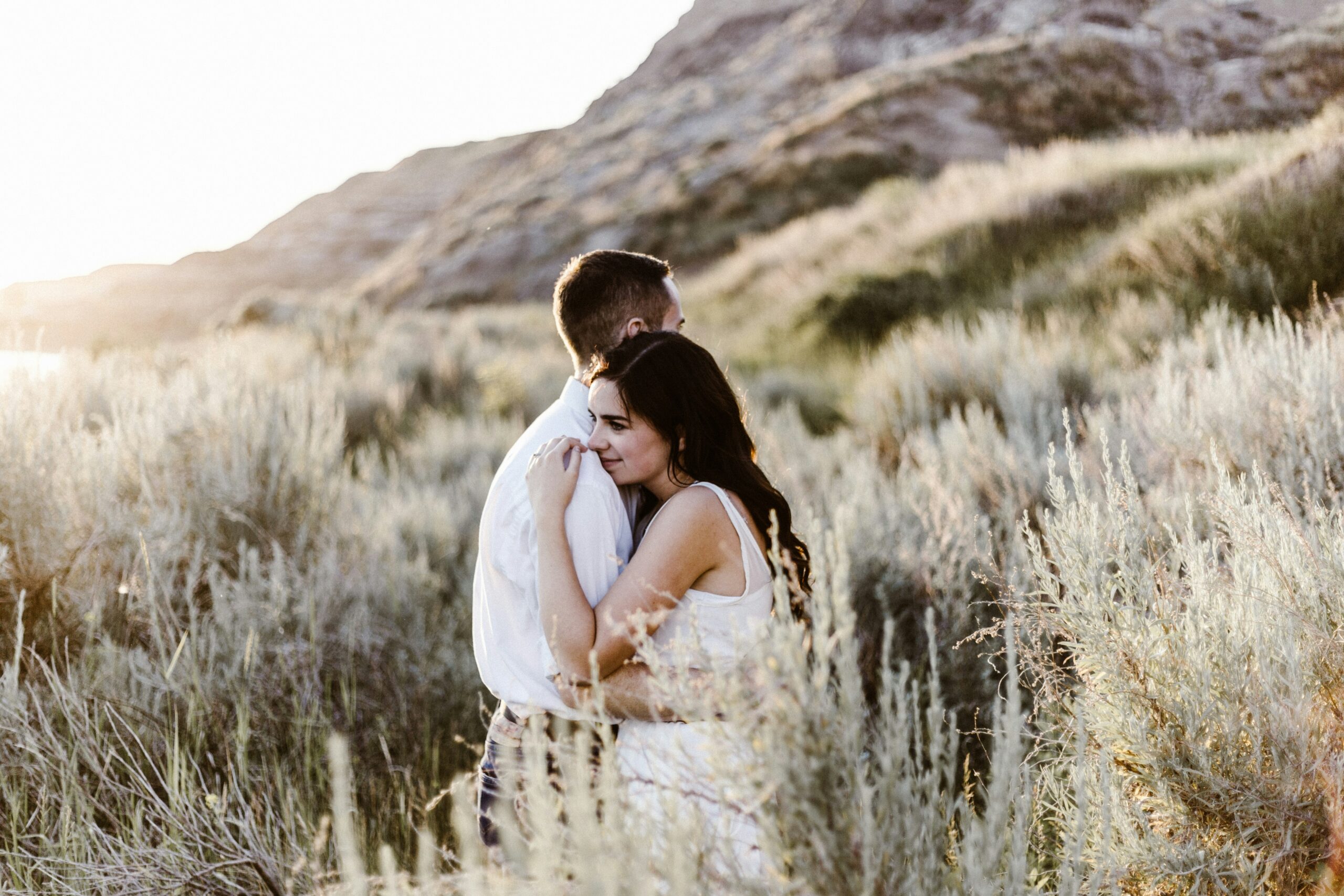 Couple hugging in grassy field. The right one.