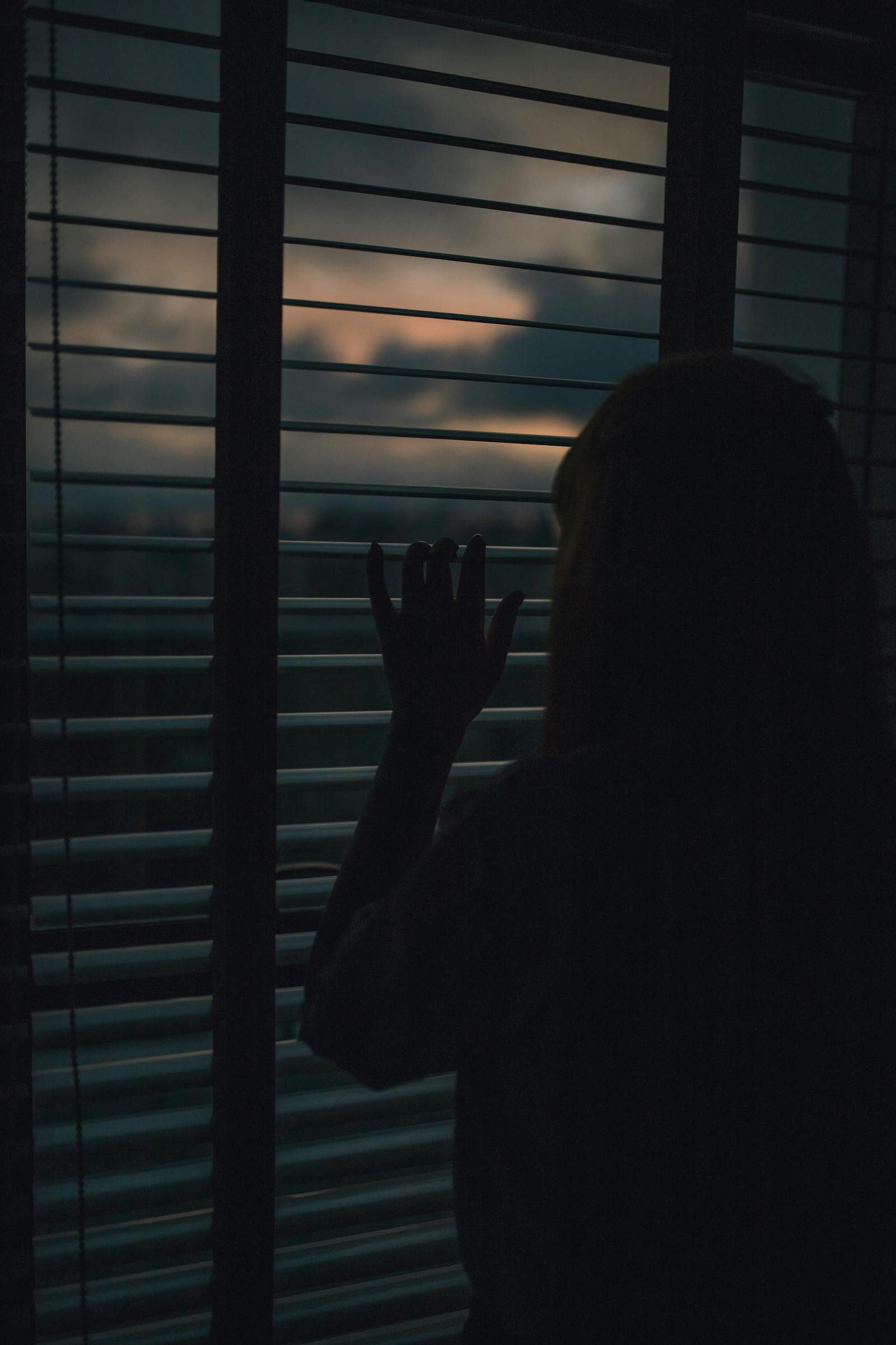 Silhouette of solo person looking out window