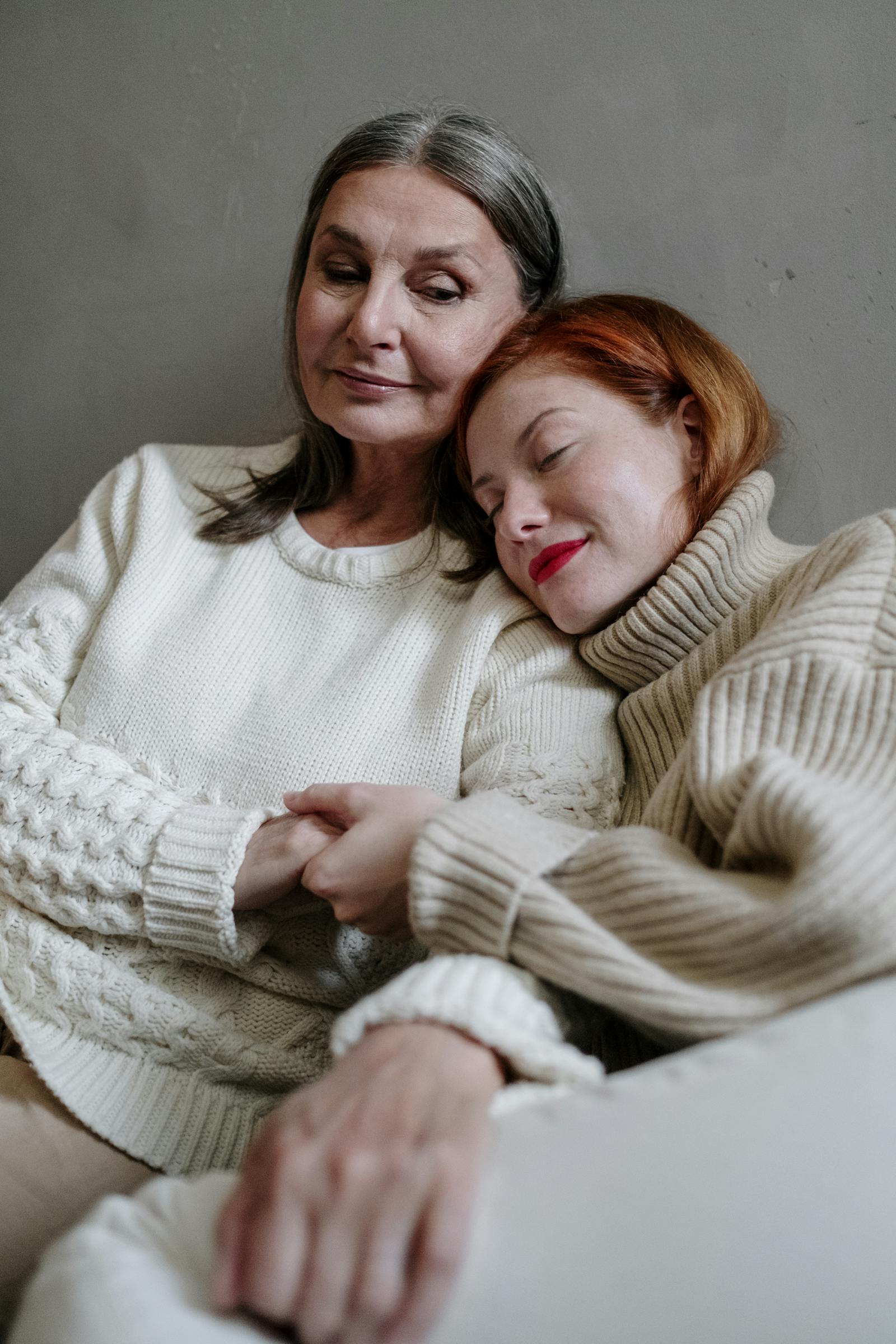 Little girl resting her head on her mothers shoulder trying to please her