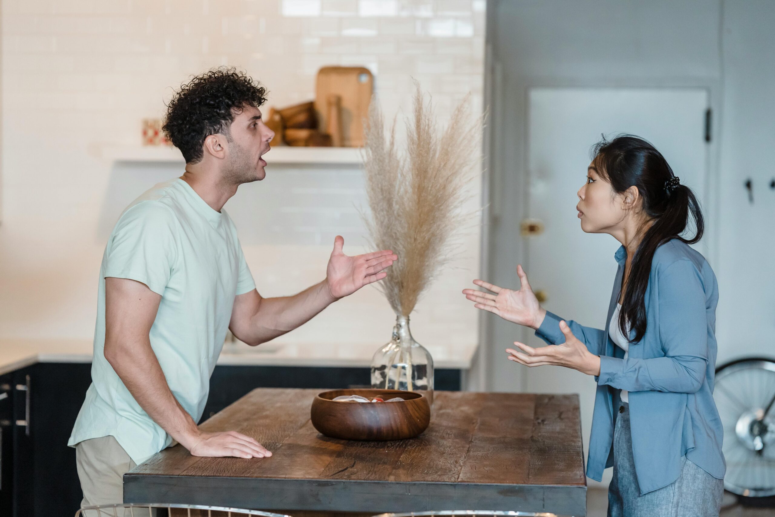 couple arguing with each other across the kitchen table. stop fighting, start connecting. here's how.
