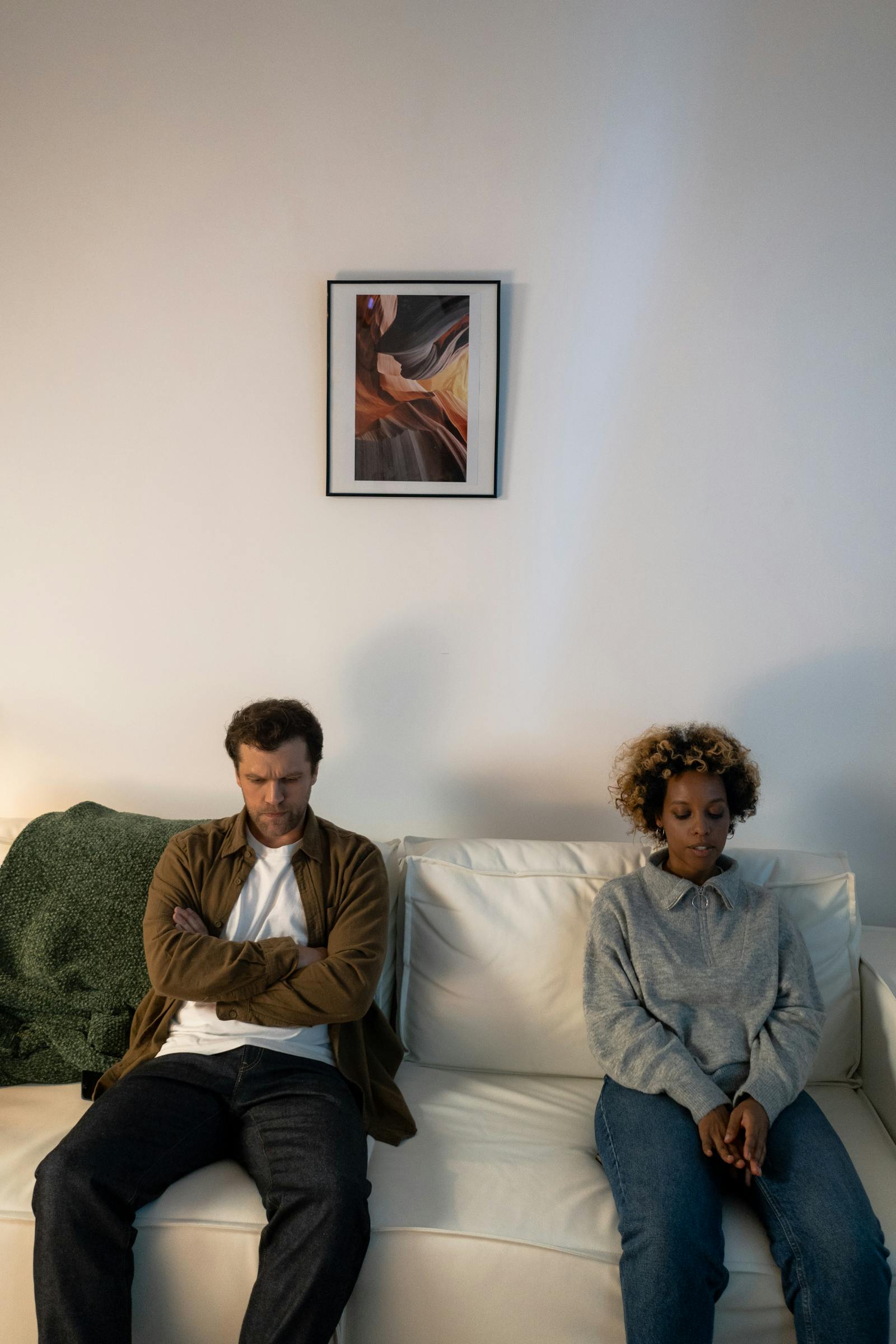 couple sitting apart on sofa needing to stop fighting and start connecting