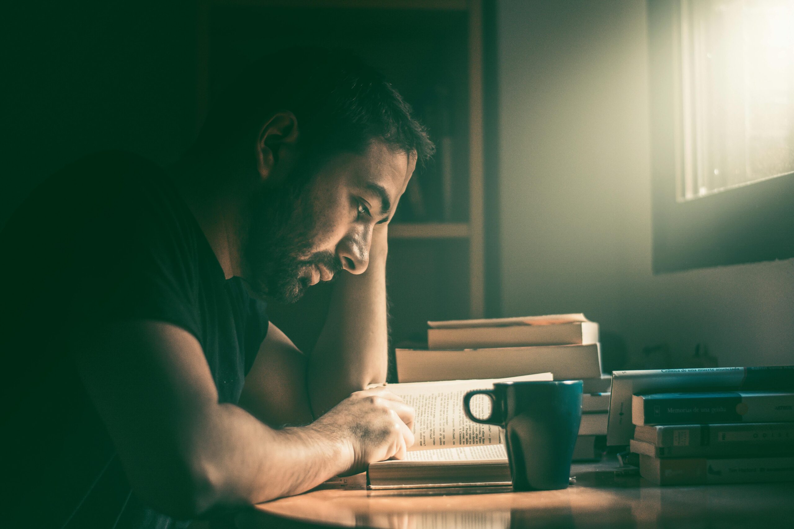 man at a desk with his head down reading a book. a lesson in becoming truly great