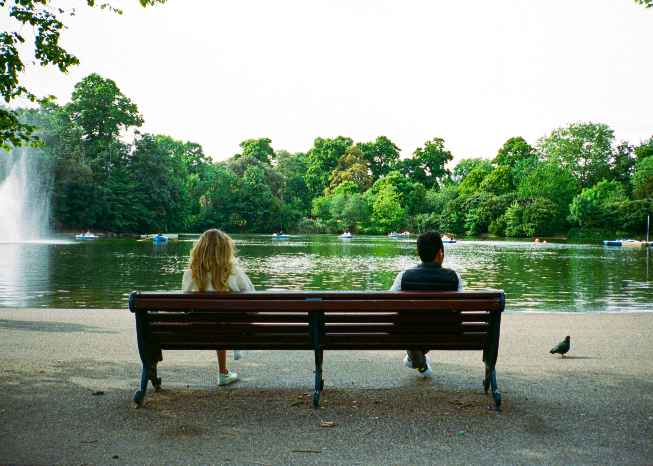 couple sitting on a park bench with some distance between them