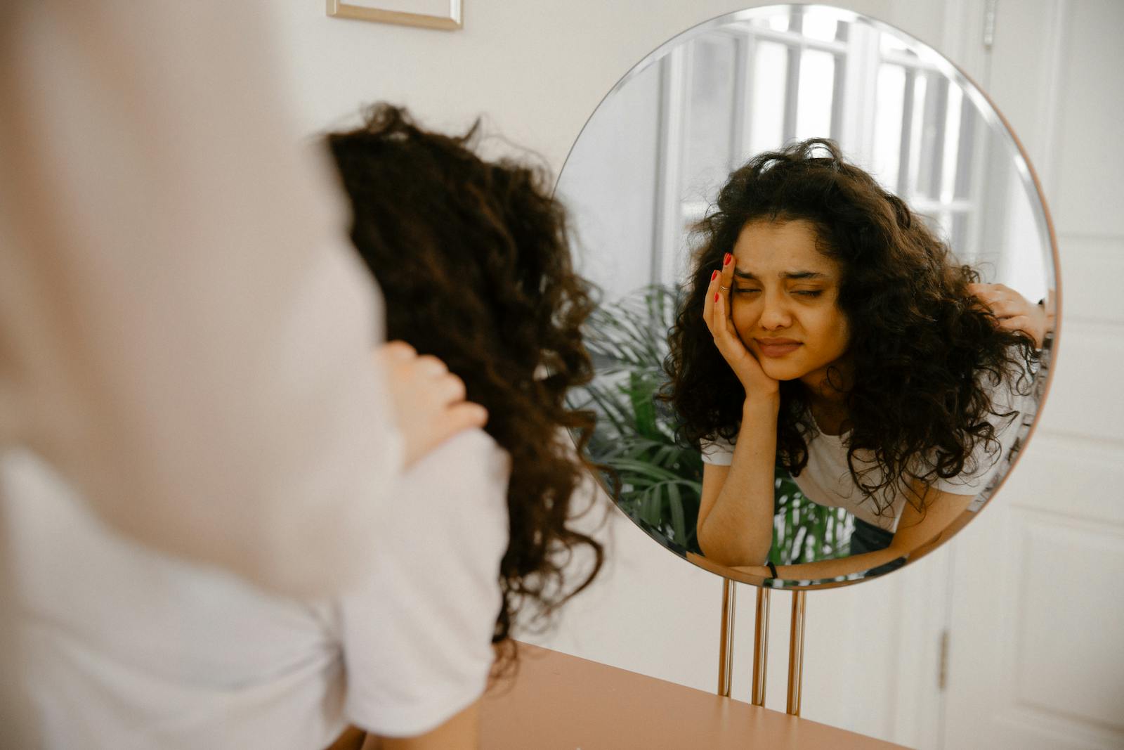 reflection of woman in mirror recognizing self-sabotaging patterns
