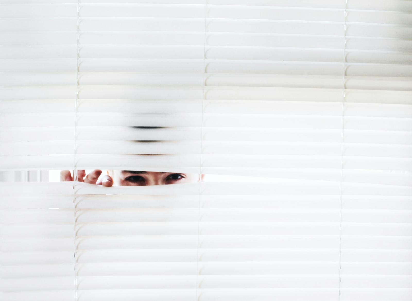 Person peeking through blinds sneakily