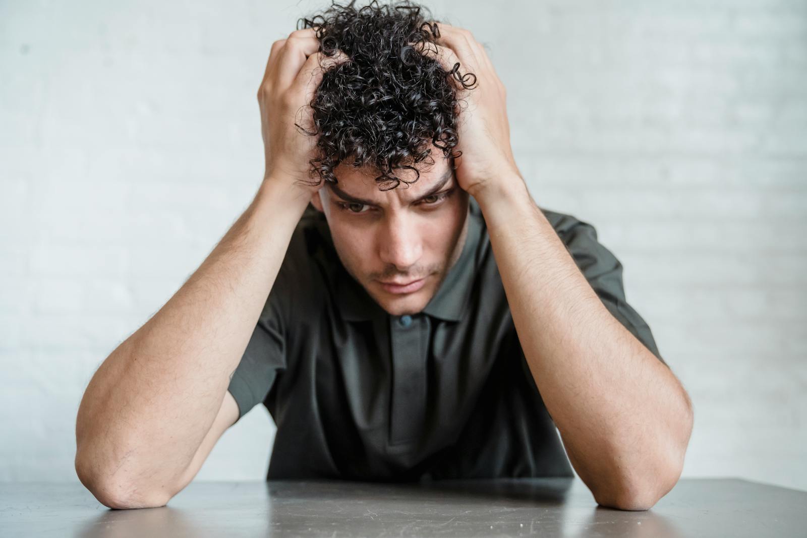 young upset man holding head in hands when feedback feels like attack