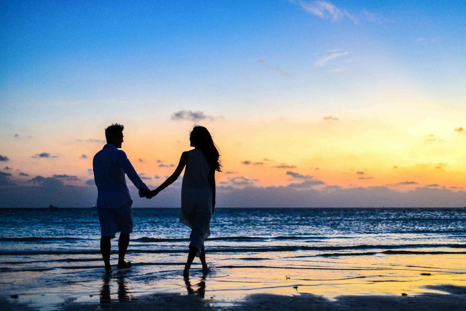 couple walking hand in hand at sunset on beach