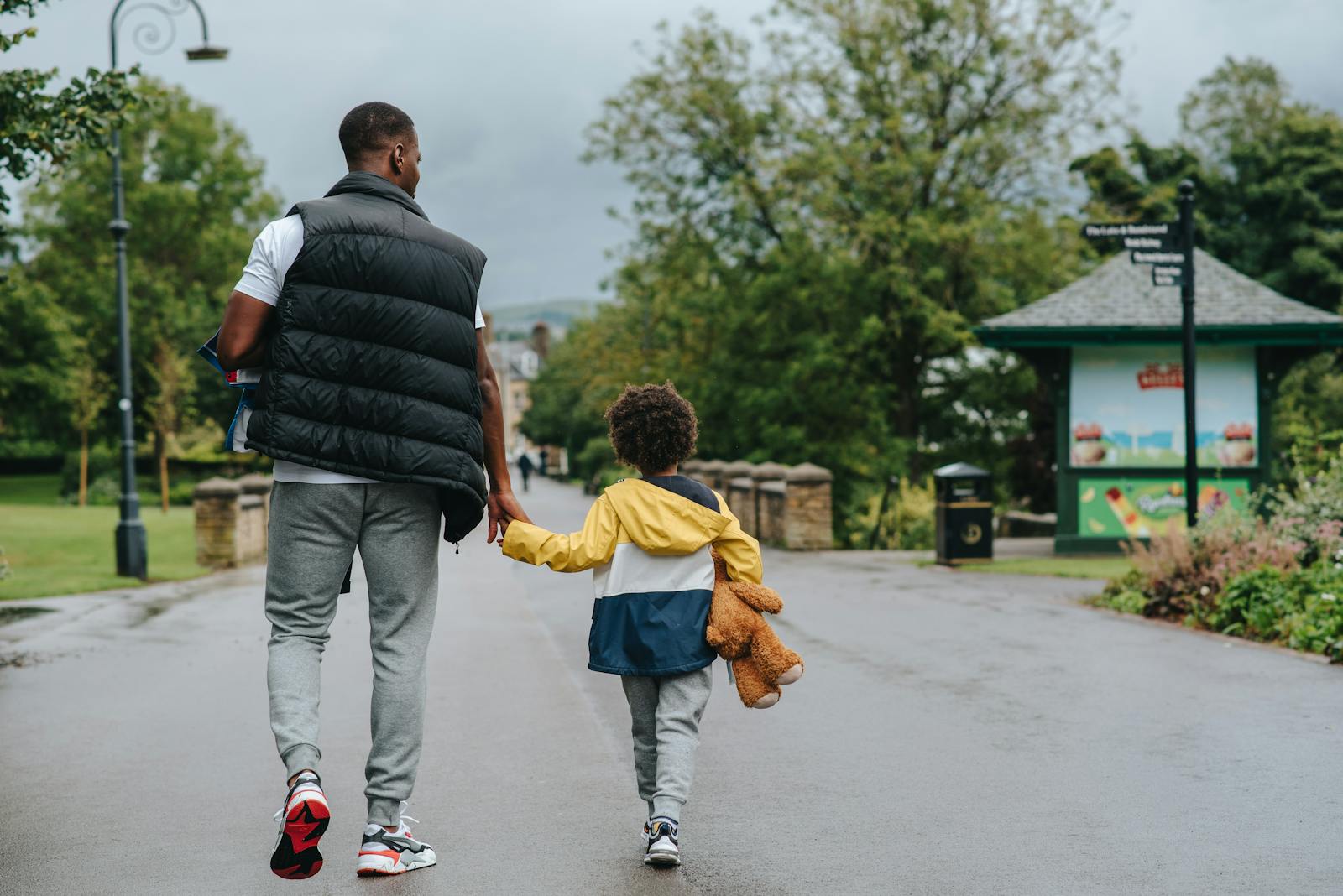 black father holding sons hand walking on road challenging gender roles per Carol Gilligan