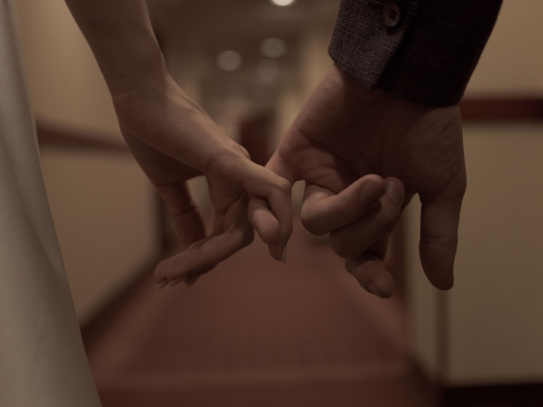 Two people linking little fingers, a small gesture of real physical closeness
