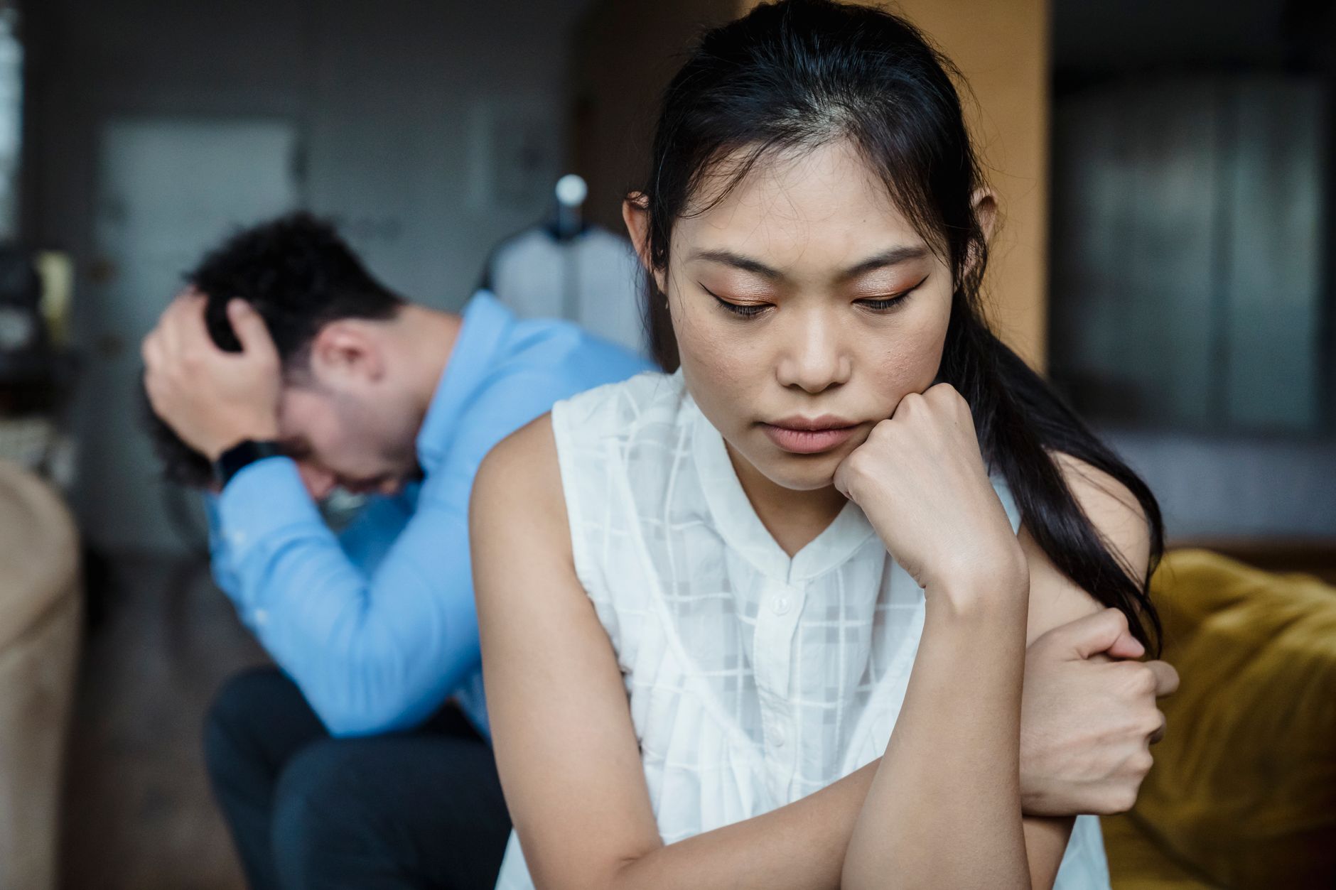 A couple sitting apart and turned away from each other in quiet distress