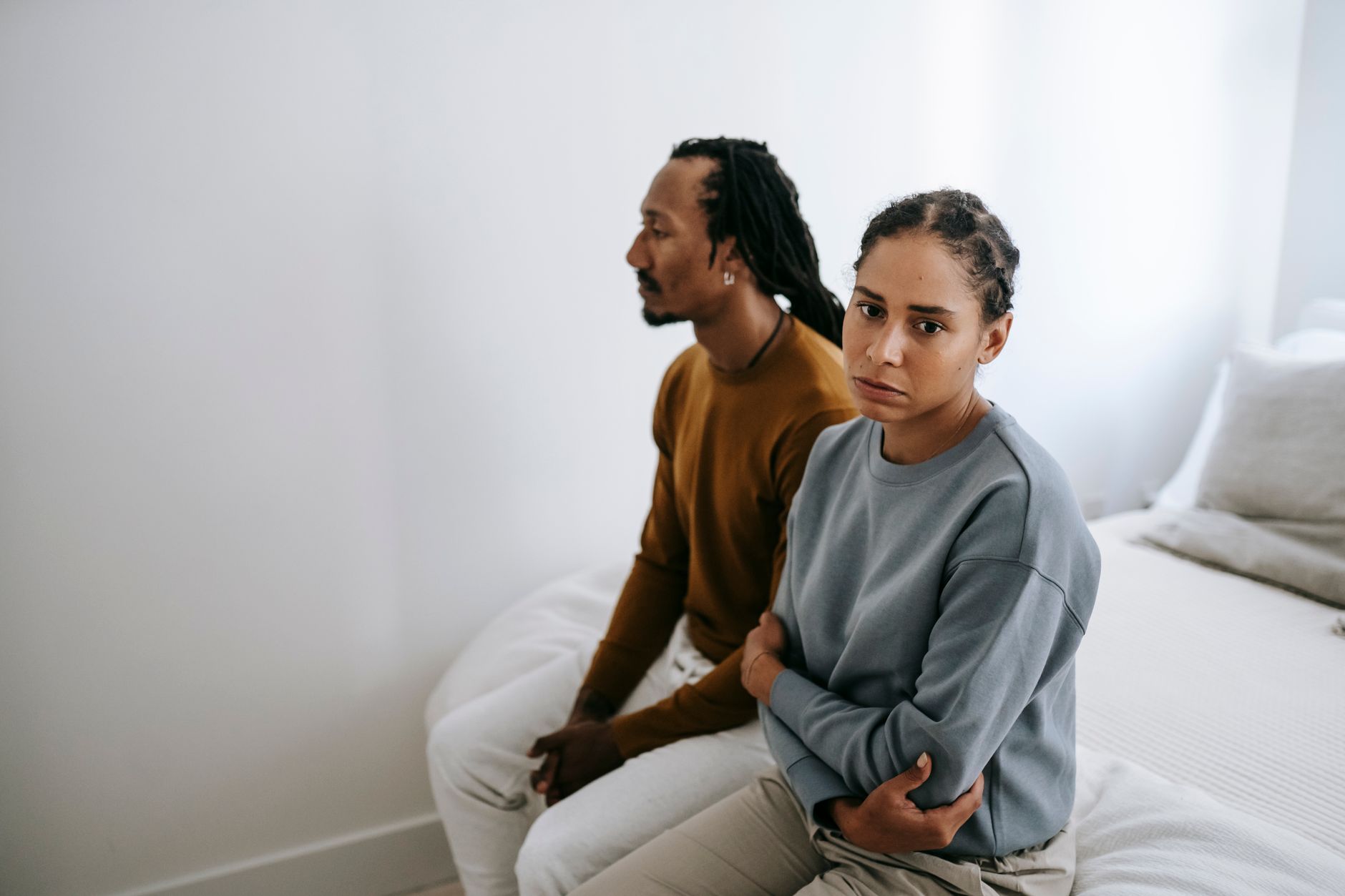 couple sitting apart on couch in tense silence