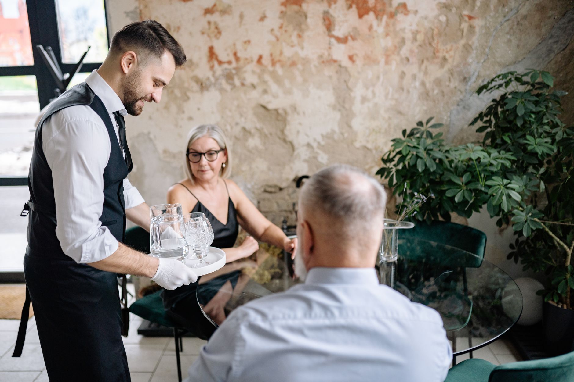 man smiling at executive while ignoring waitstaff at restaurant